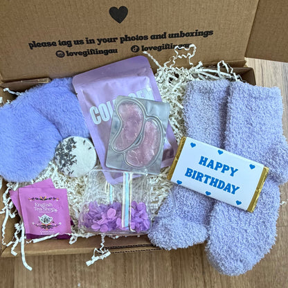 Gift box with plush toys, a card, and a small gift on a wooden floor.