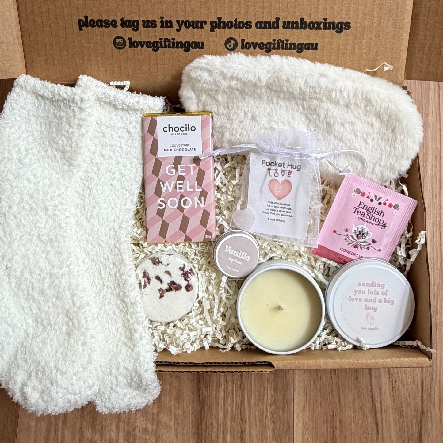 Gift box with products and a blanket on a wooden surface