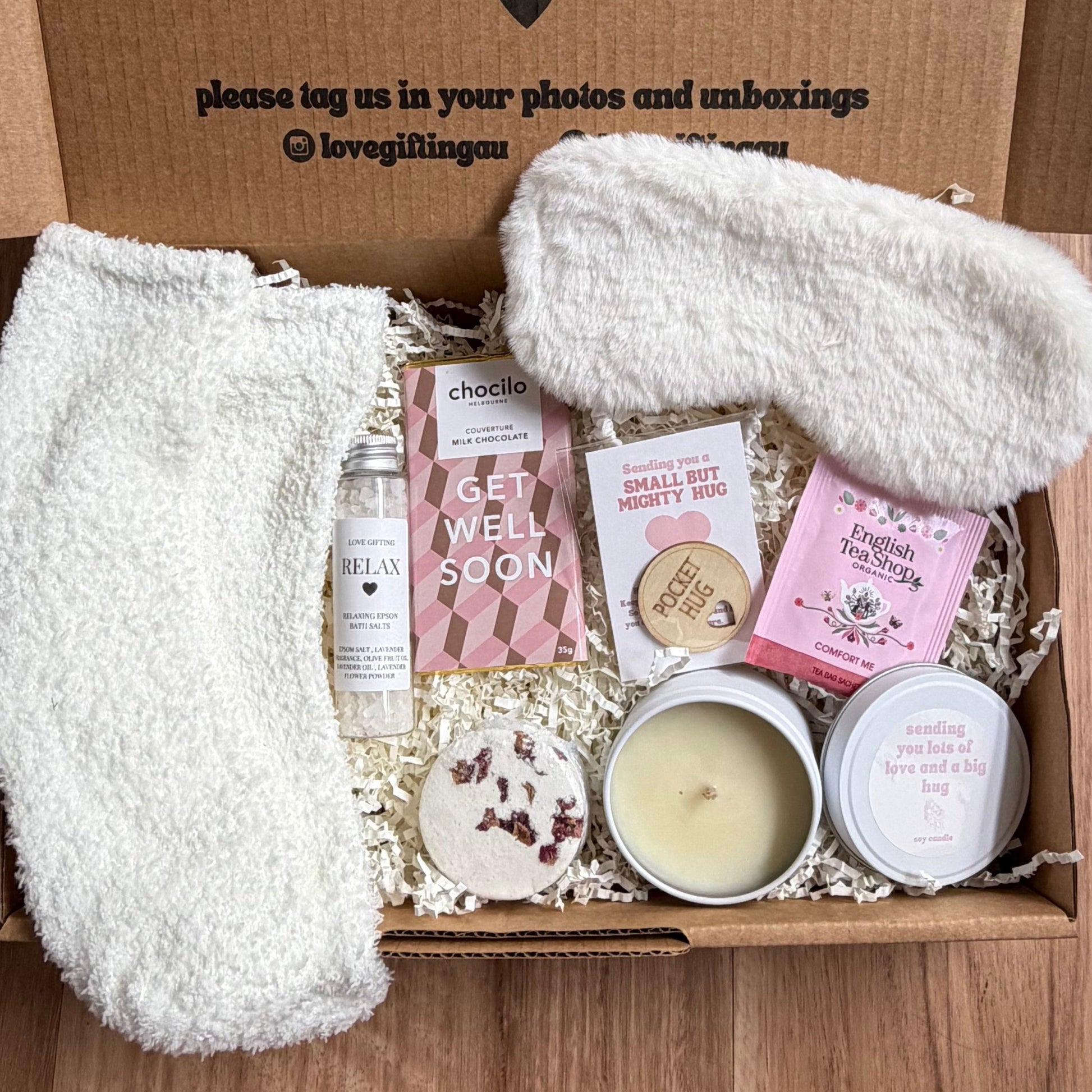 Box of self-care items with a message on the lid, placed on a wooden surface.