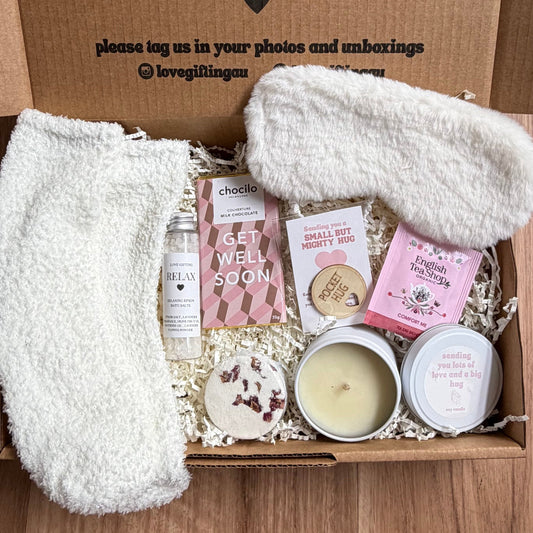 Box of self-care items with a message on the lid, placed on a wooden surface.