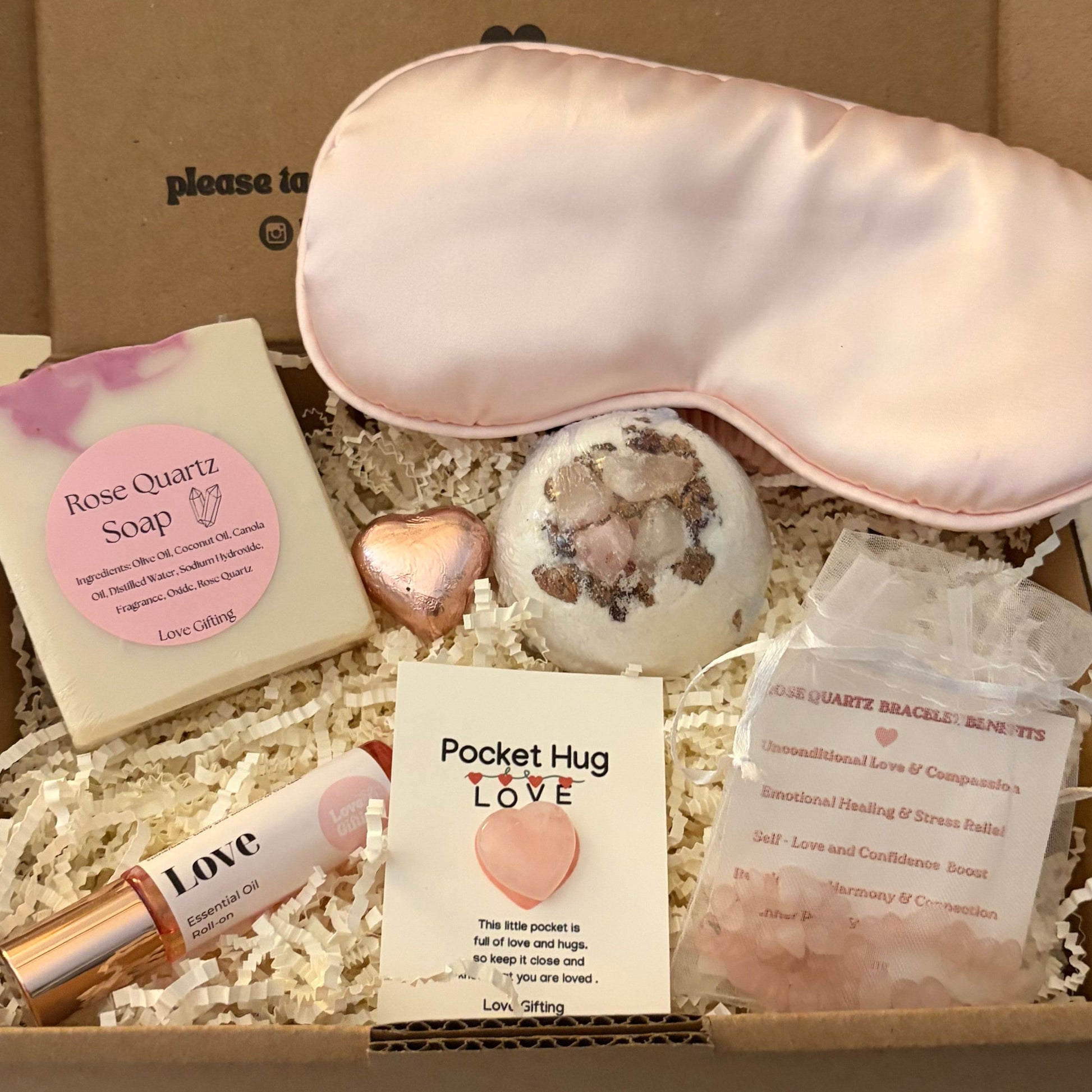 Gift box with rose quartz soap, bath bomb and bracelet pink eye mask, soap, and a card, with text on the box.
