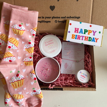 Birthday gift set with pink cupcake-patterned socks, a small bowl, and a 'Happy Birthday' card in a box.
