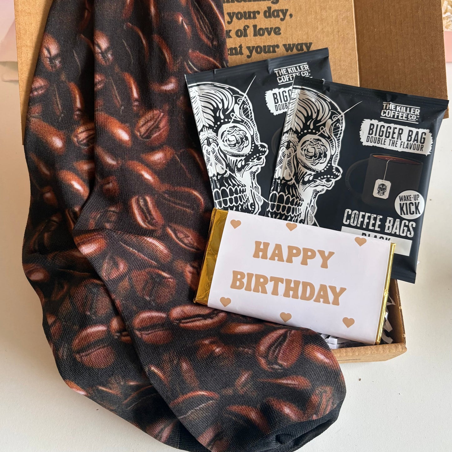 Coffee-themed socks and gift items including coffee bags and a birthday card on a white surface.