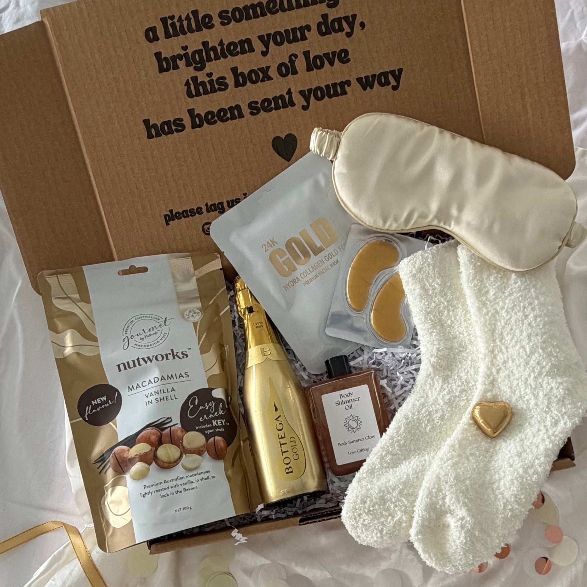 gift box including prosecco, vanilla nuts, cream socks, gold sleep mask, lapcos facemask, shimmer oil