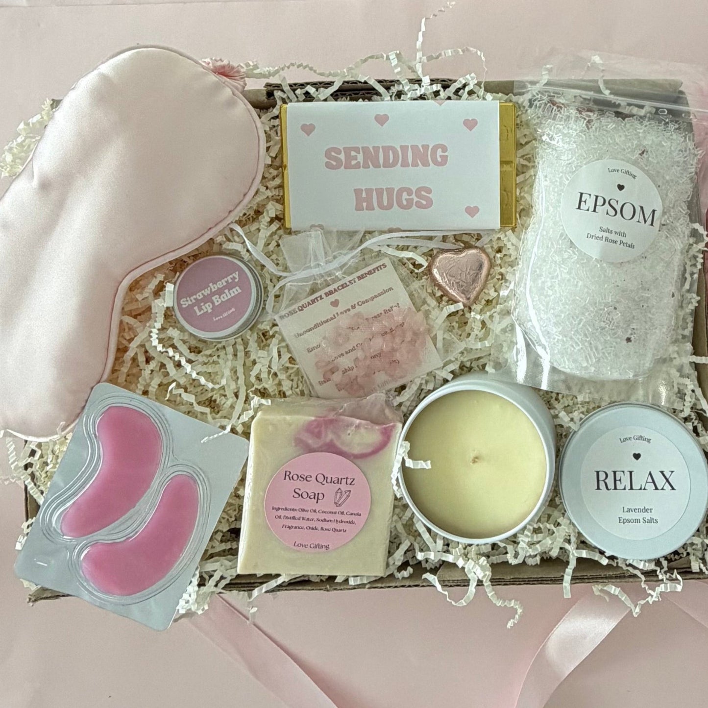 Pamper gift box includes epsom bath slats, sleep mask, under eye mask, candle, rose quartz soap, rose quartz bracelet, strawberry lipbalm, chocolate heart, sending hugs chocolate