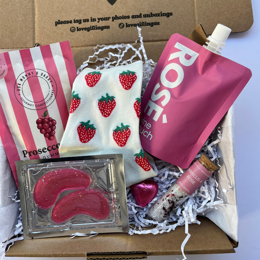 Ladies Gift Box with strawberry Socks, under eye mask, prosecco gummies and wine pouch , Bath Salts in tube and chocolate heart.