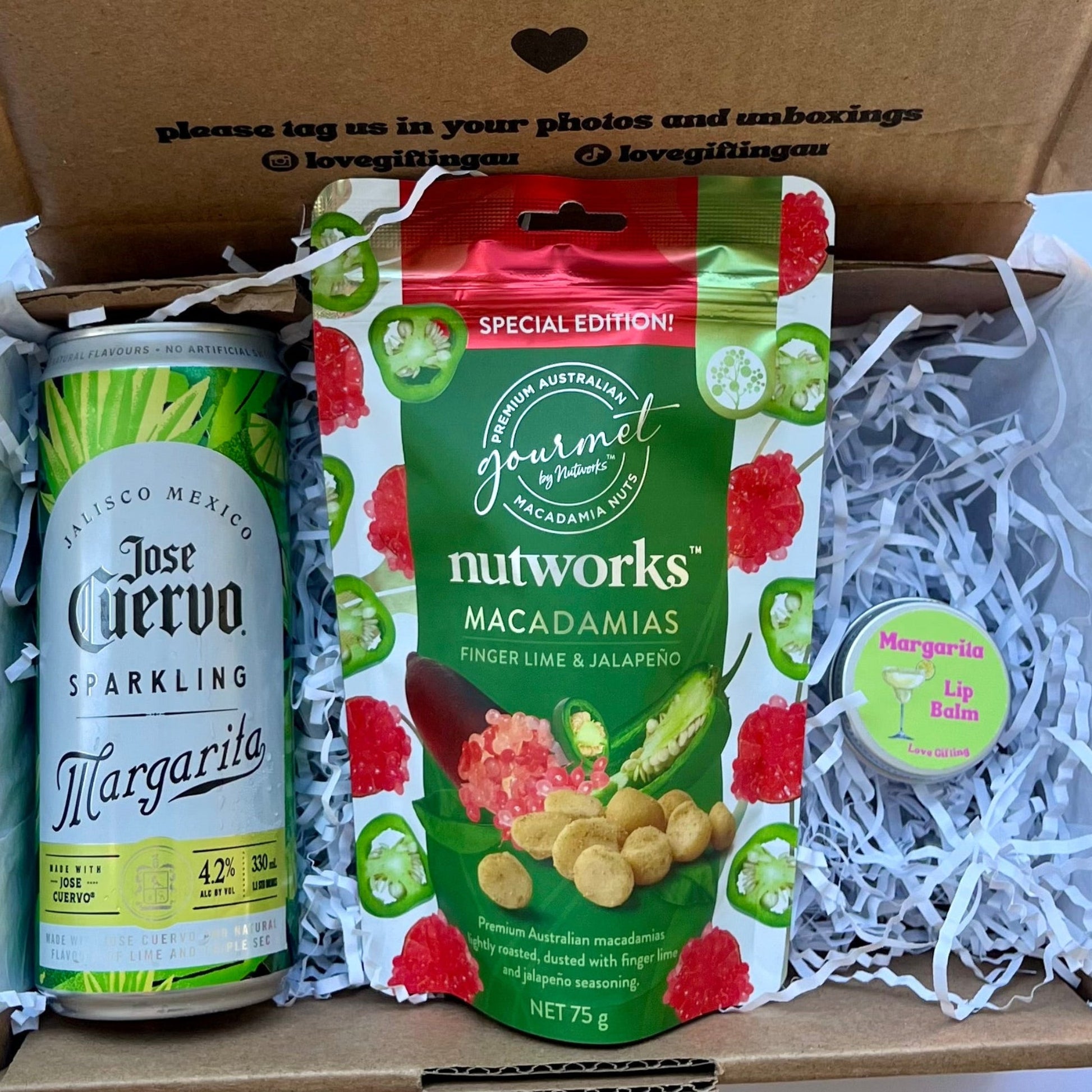 Gift box with Jose Cuervo Margarita can and Nutworks macadamia nuts on a light blue background