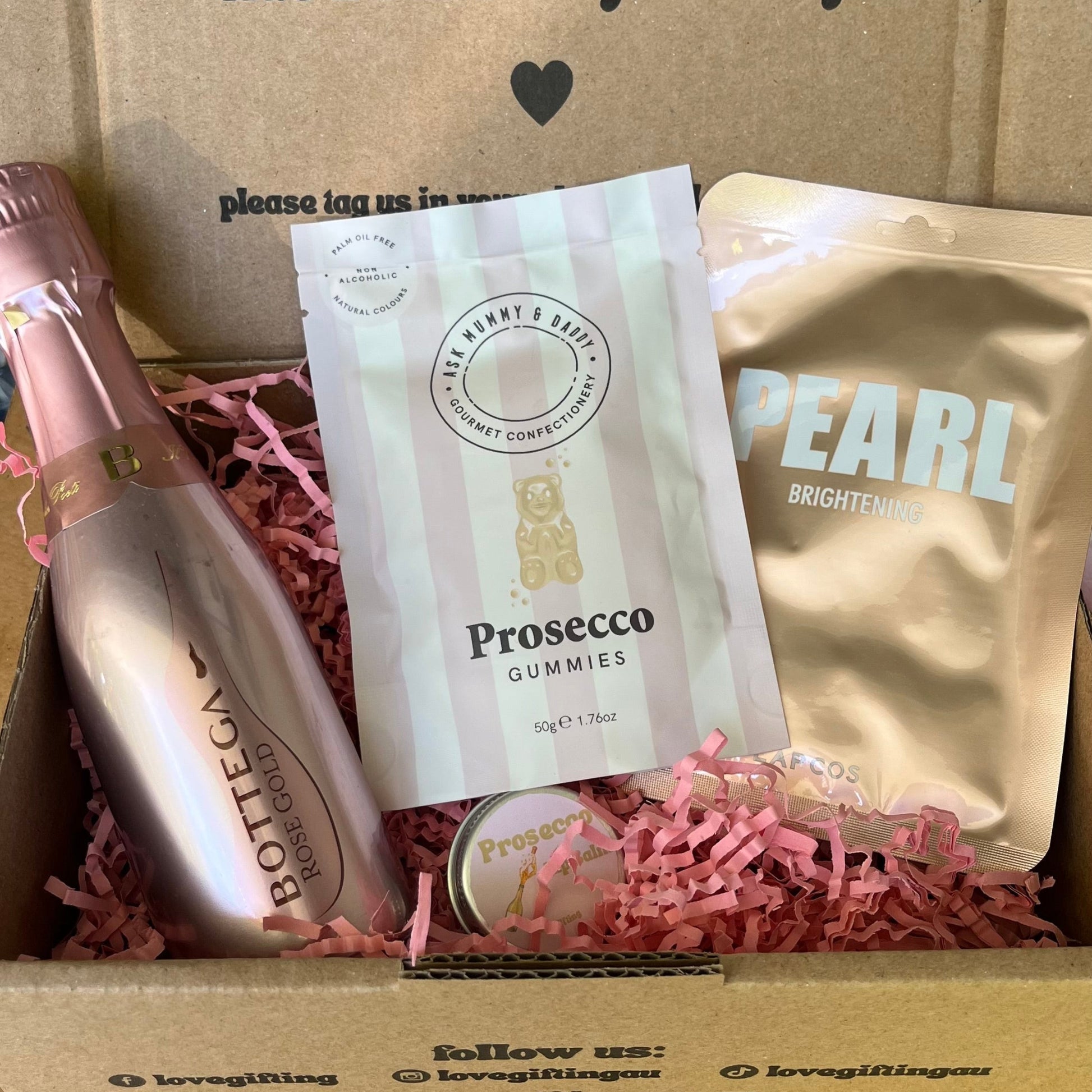 Gift box with Prosecco bottle, gummies, and pearl product inside, featuring a message on the box.