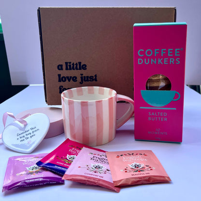Coffee dunkers packaging with a pink mug and assorted packets on a white surface.