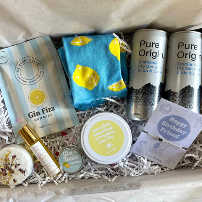 Gift box with gin-themed items including gummies, a bottle, and a card.