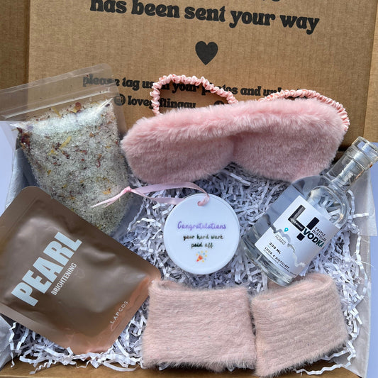 Gift box with pink eye masks, a bottle of vodka, socks, goddess Salts, congratulations keepsake.