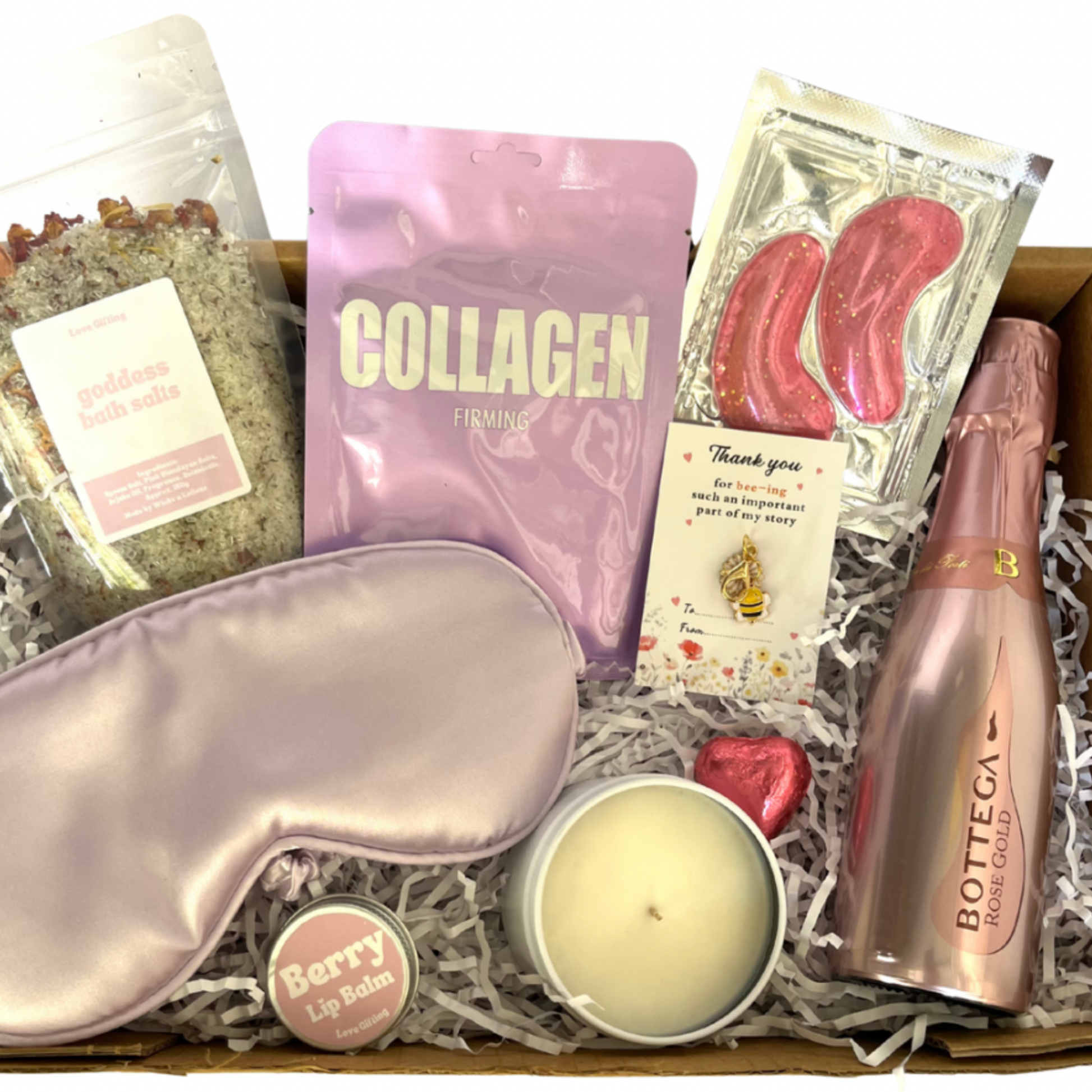 Gift box with sleep mask, collagen powder, candle, and other items on a white background