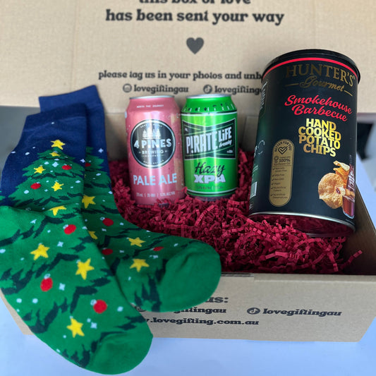 Gift box with Christmas-themed socks, beer cans, and potato chips.