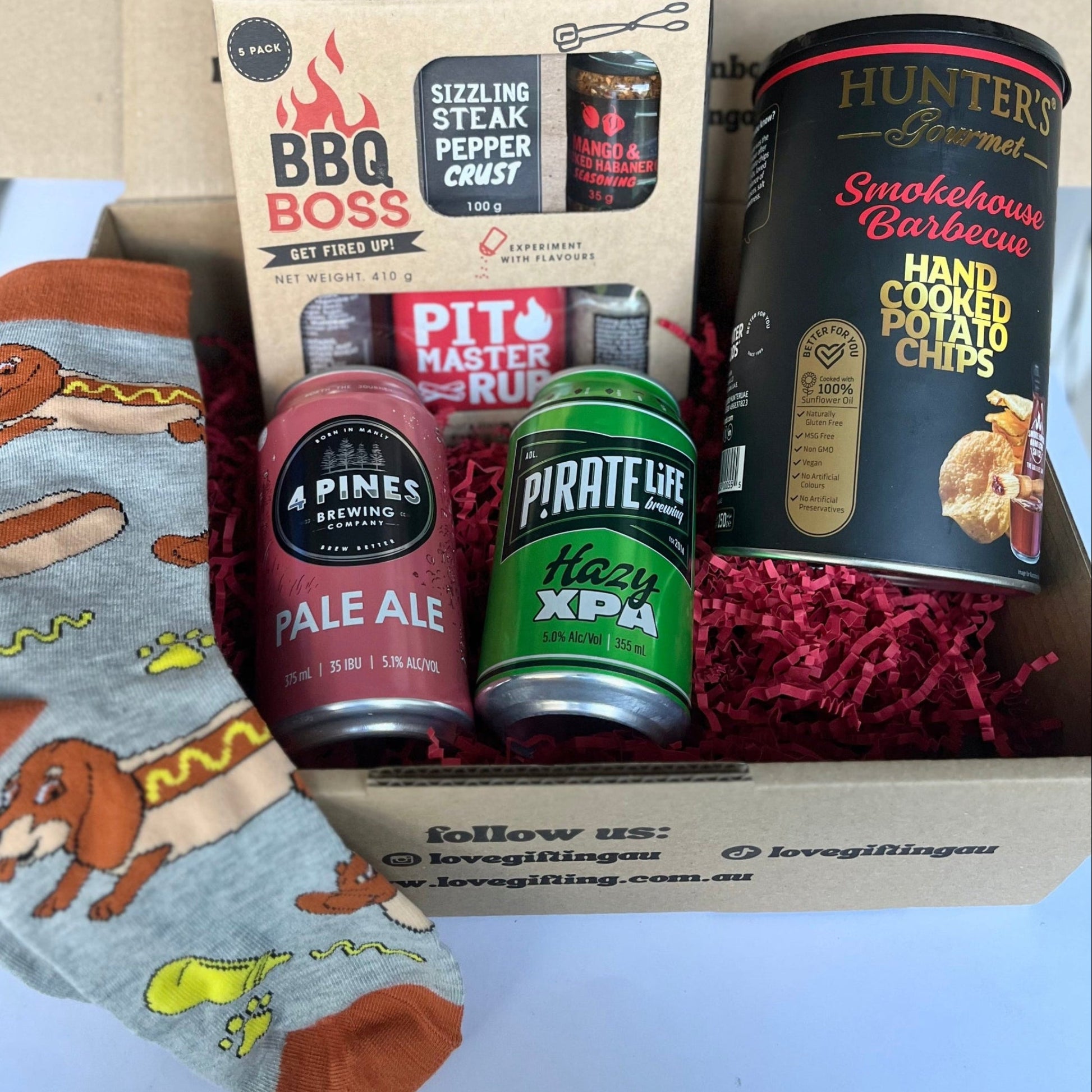 Gift box with beer bottles, snacks, and a can of sardines on a white background