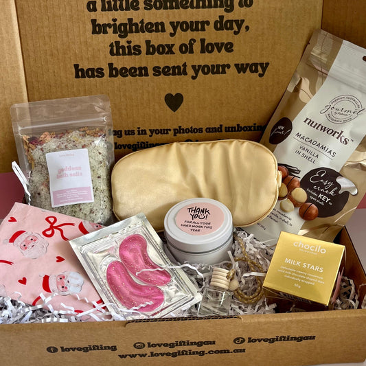 Gift box with various items including a soap bar, cookies, and a card on a white background.