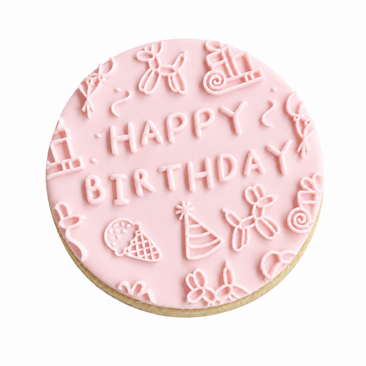 A round birthday cookie with light pink icing, featuring the words 'HAPPY BIRTHDAY' in raised letters surrounded by small festive illustrations like balloons, an ice cream cone, a party hat, and swirls, on a white background.