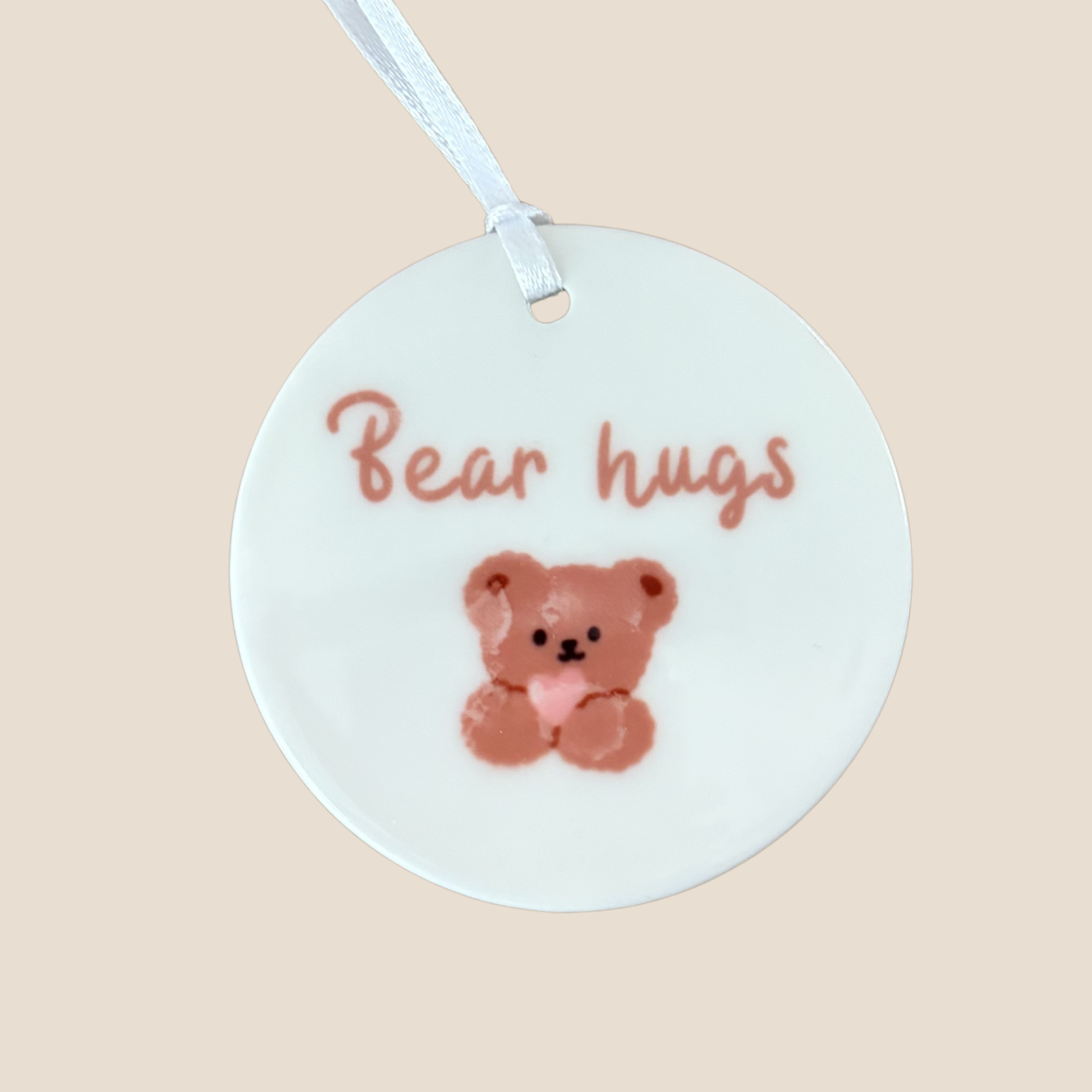 Round white tag with a teddy bear illustration and 'Bear hugs' text on a beige background