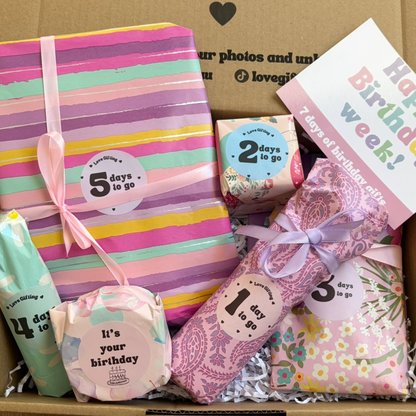 Box of birthday-themed products with countdown labels and a card, set against a cardboard backdrop.