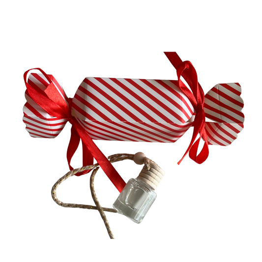 Decorative candy with red and white stripes and a small bottle attached, on a white background