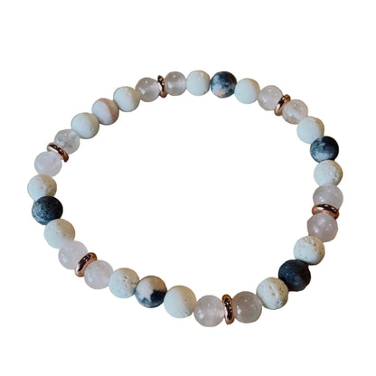 Beaded bracelet with white, black, and rose gold accents on a wooden surface