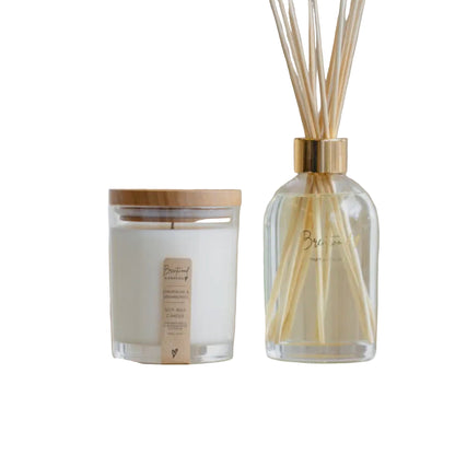 Candle and diffuser set on a stone surface with a neutral background