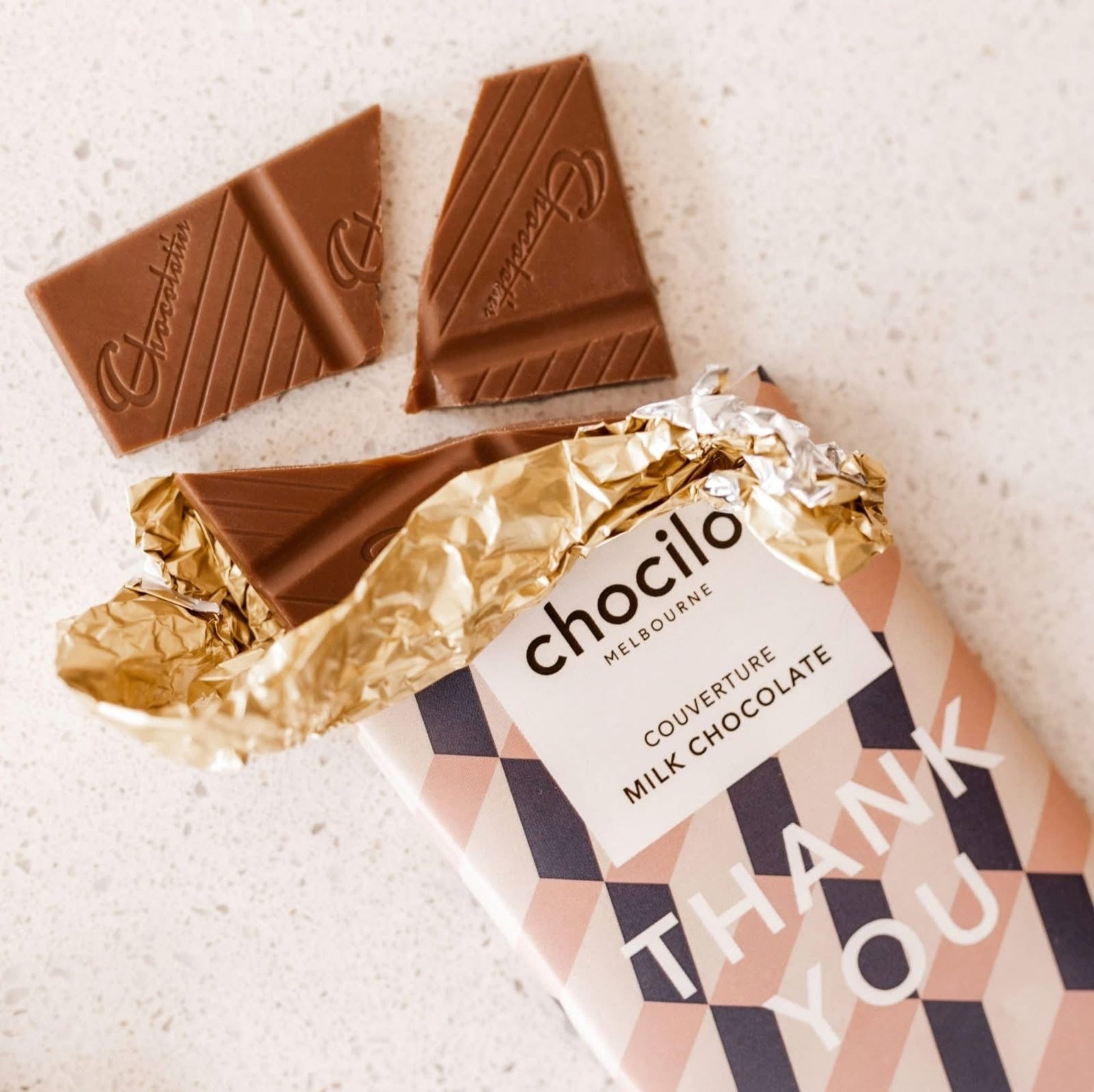 Chocolate bars with gold foil and 'chocilo' packaging on a light background
