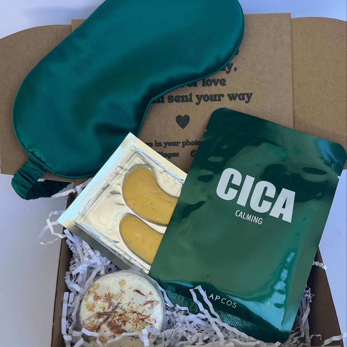 Box containing a green sleep mask, Cica product, and other items on a white background