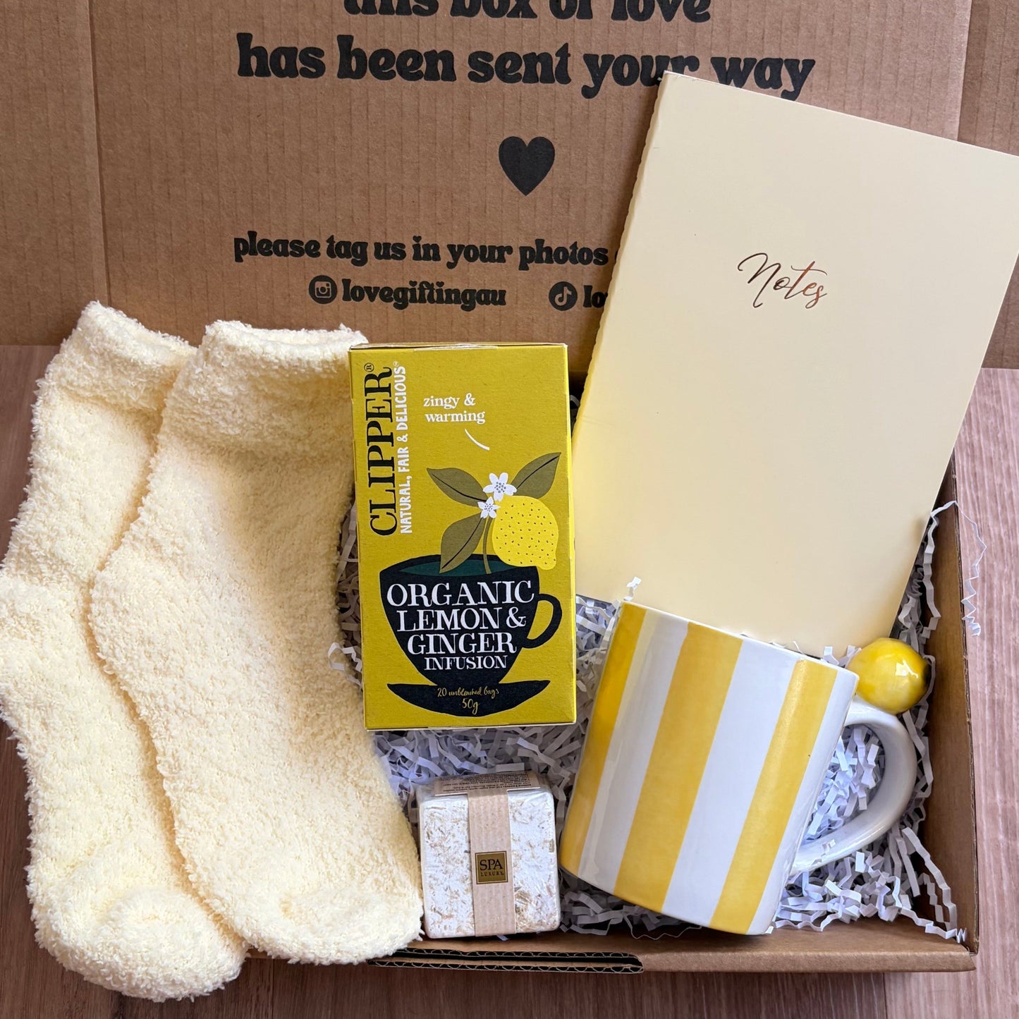 Gift box with a card, socks, lemon tea, and other items on a wooden surface