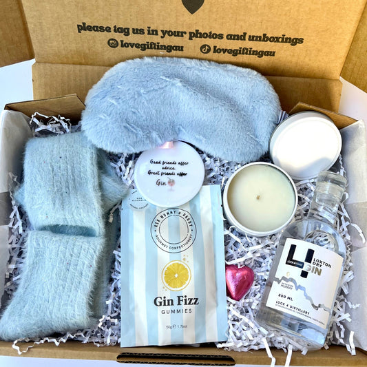 Gift box with light blue socks, Gin Fizz gummies, and other items, with a message on the lid.