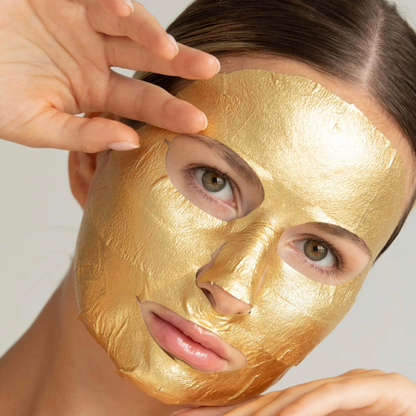 Person wearing a gold face mask with a hand adjusting it.