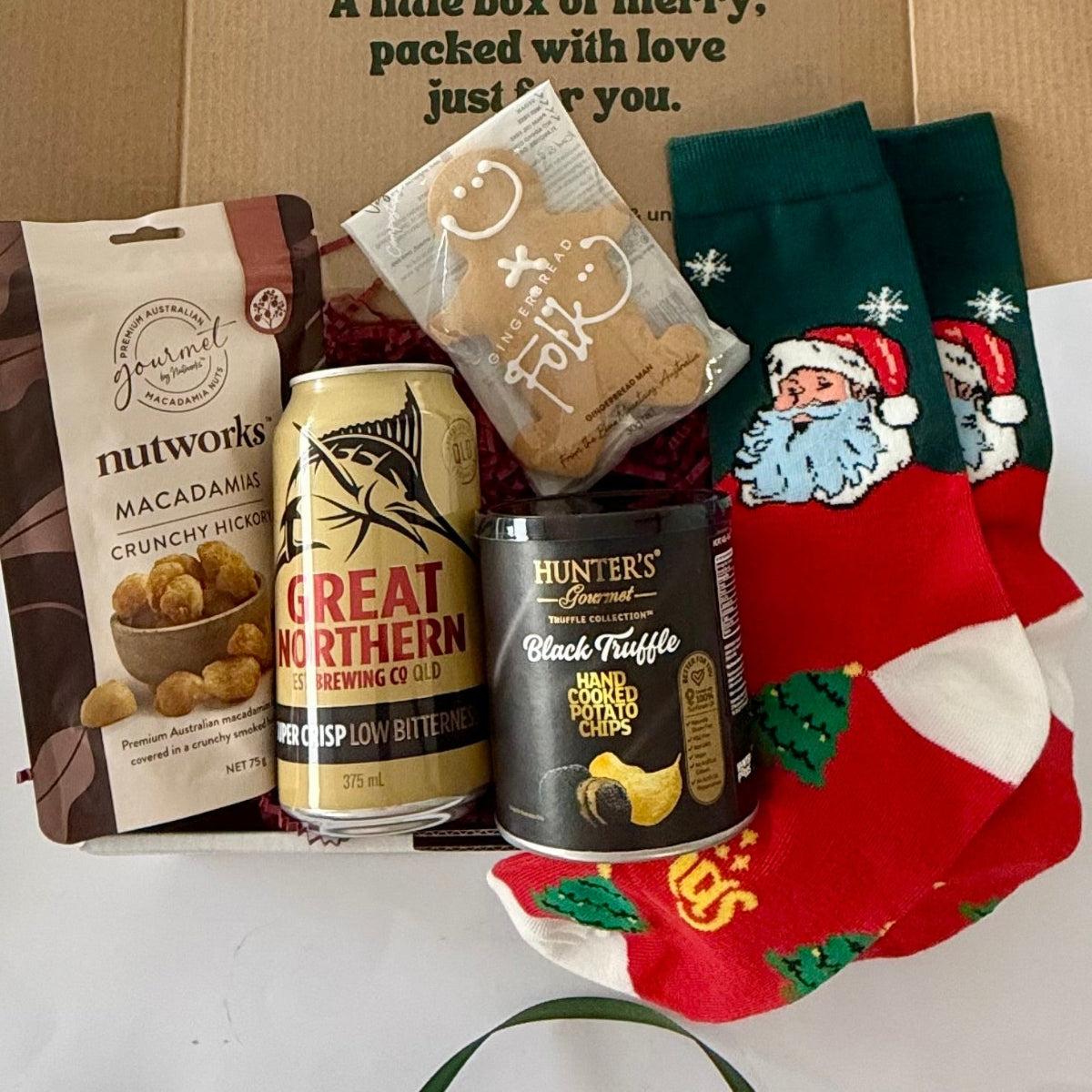 Santa's Ultimate Snack Stash men's Christmas gift box with Great Northern beer, Nutworks Hickory Macadamias, black truffle chips, gingerbread man and Santa socks.