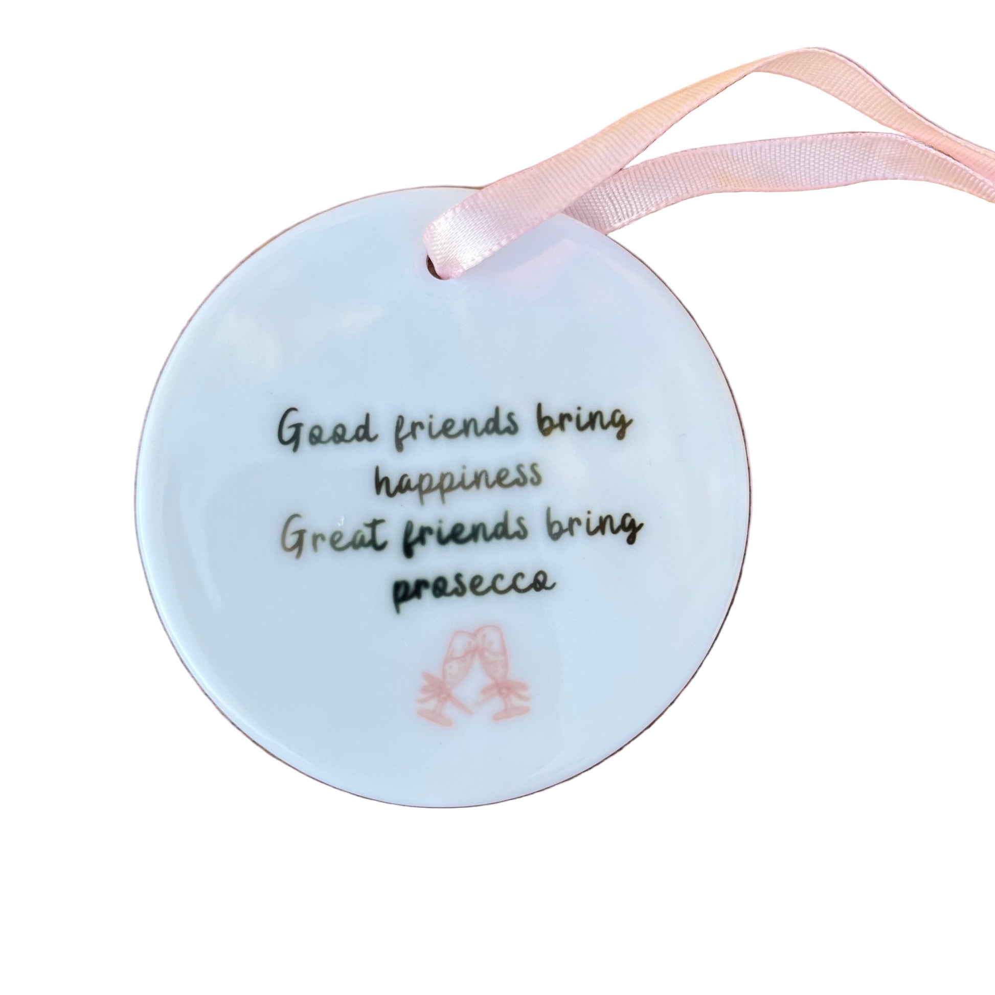 Round white ornament with text and a pink ribbon on a wooden surface