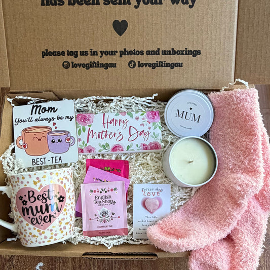 Gift box with tea, socks, and a candle on a wooden surface