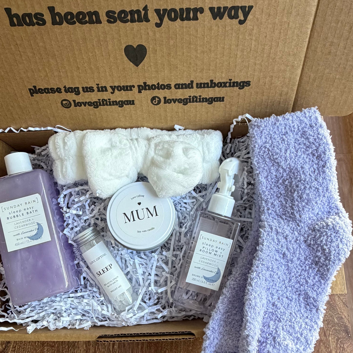 Gift box with bath products and a pair of socks on a wooden surface