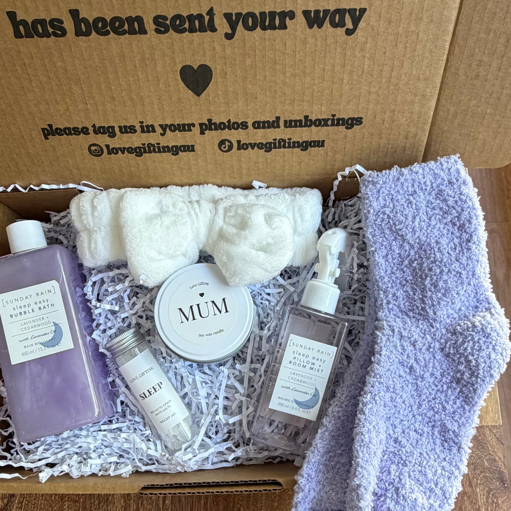 Gift box with bath products and a pair of socks on a wooden surface