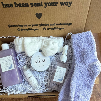 Gift box with bath products and a pair of socks on a wooden surface