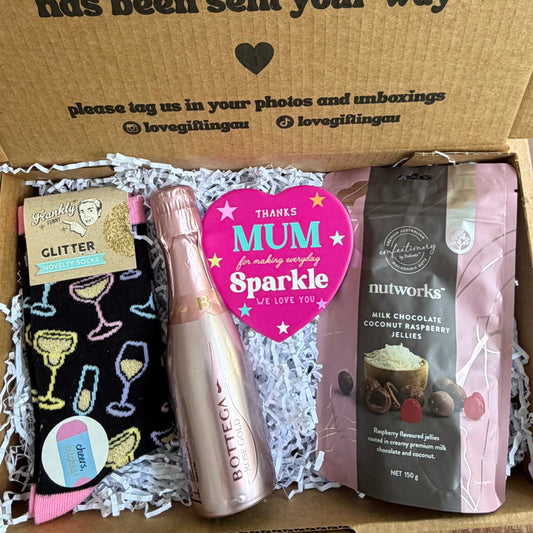 Box of mothers day goodies with a card inside on a wooden floor