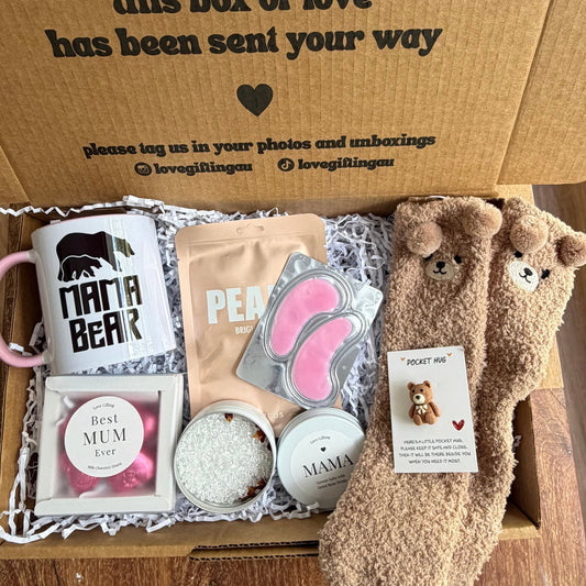 Box of assorted items including a mug, socks, and a plush toy on a wooden surface.