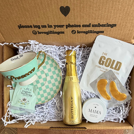 Gift box with a bottle, cards, and other items on a wooden surface.