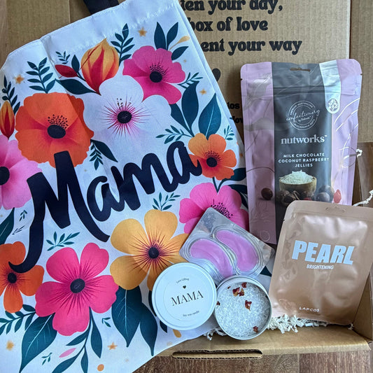 Gift box with 'Mama' card, bath bombs, and other items on a wooden surface