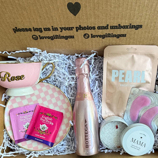 Mothers day Gift box with various items including a bottle, a bag, and other small products on a wooden surface.