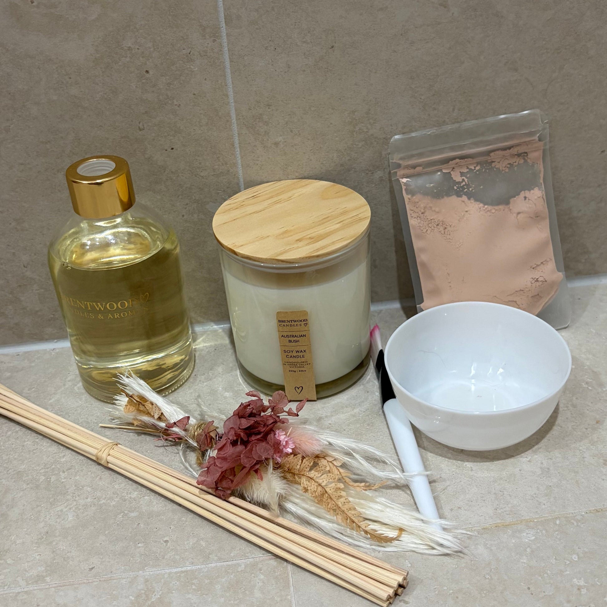 Bathroom counter with a candle, bottle, bowl, and reed diffuser on a tiled surface.