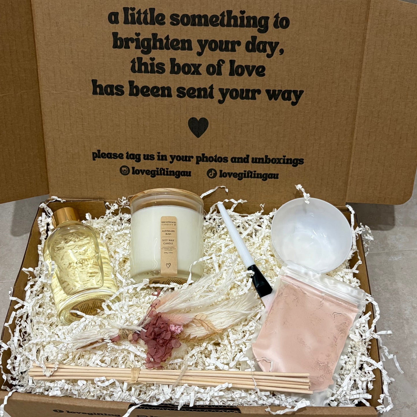 Gift box with candles, soap, and other items on a neutral background