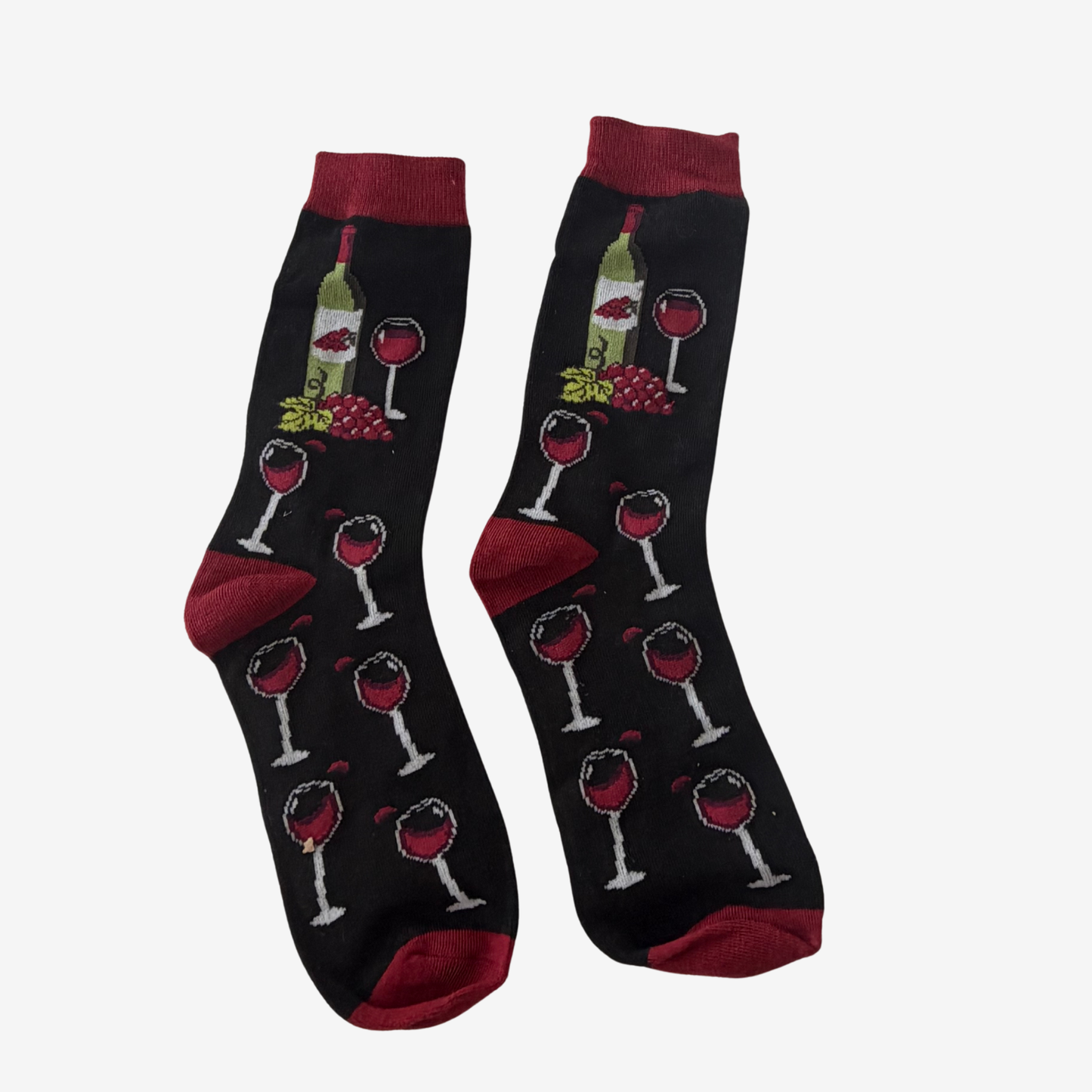 A pair of black crew socks with a wine-themed pattern featuring wine bottles, glasses, grapes, and red heels, toes, and cuffs, displayed against a light gray background.