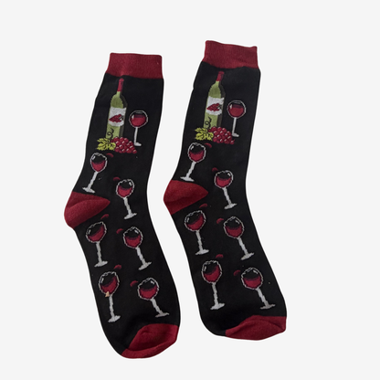 A pair of black crew socks with a wine-themed pattern featuring wine bottles, glasses, grapes, and red heels, toes, and cuffs, displayed against a light gray background.