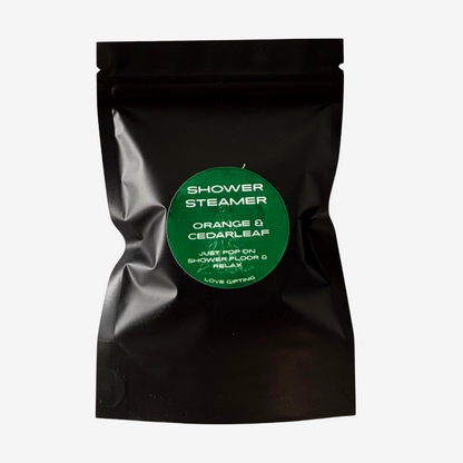 Love Gifting Orange & Cedarleaf Shower Steamers in black packaging with green label, refreshing aromatic shower treats for self-care and gifting.