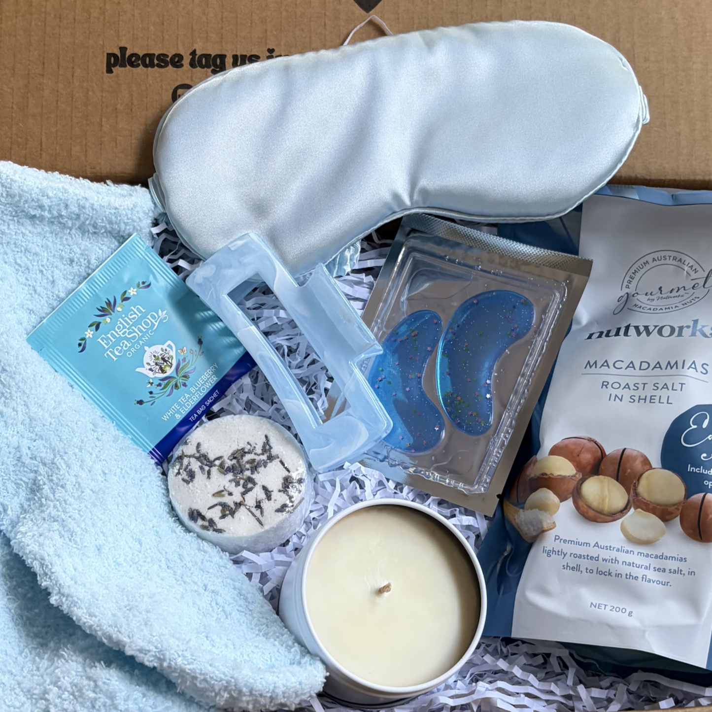 Gift box with  calm , relaxing items vibes, including a sleep mask, candle, shower steamer and macadamia nuts.
