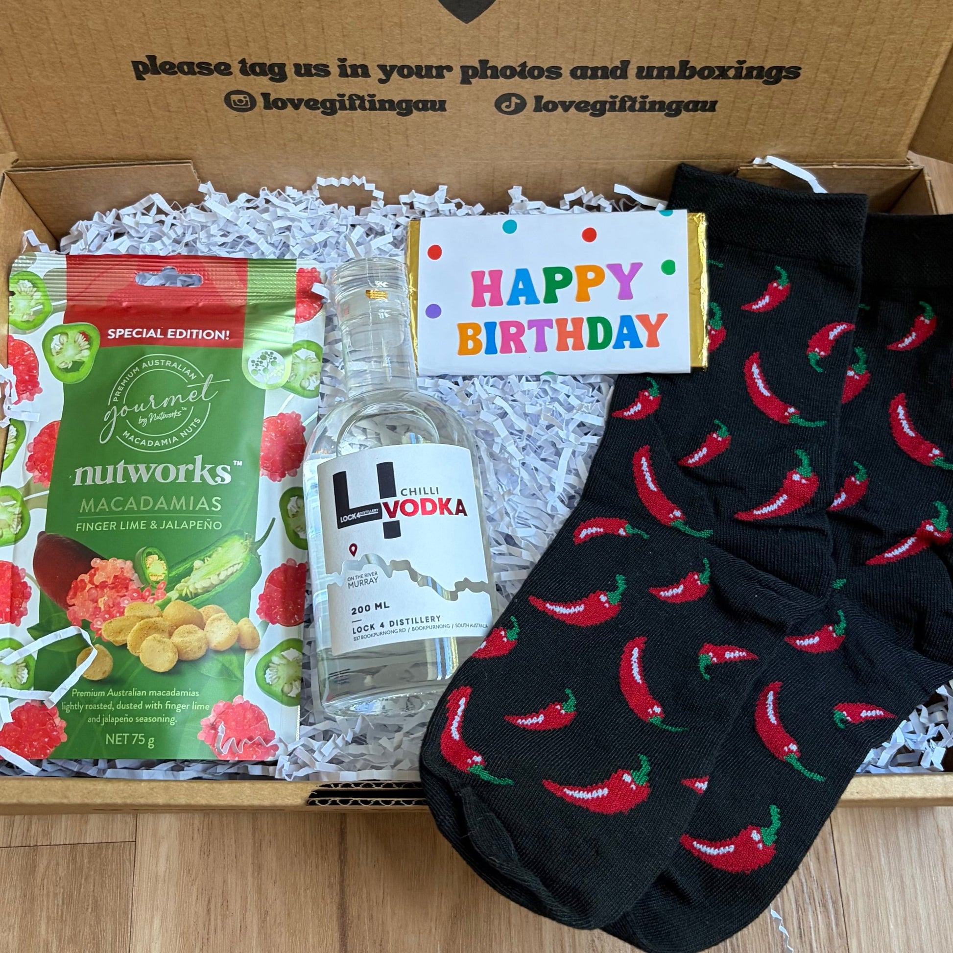 Birthday gift box with vodka, snacks, and socks on a wooden surface