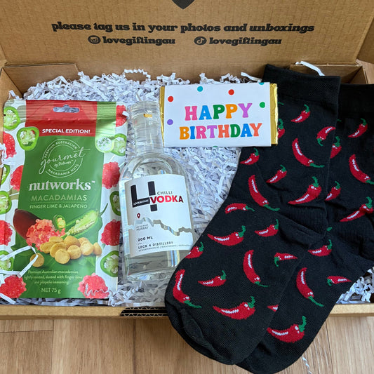 Birthday gift box with vodka, snacks, and socks on a wooden surface