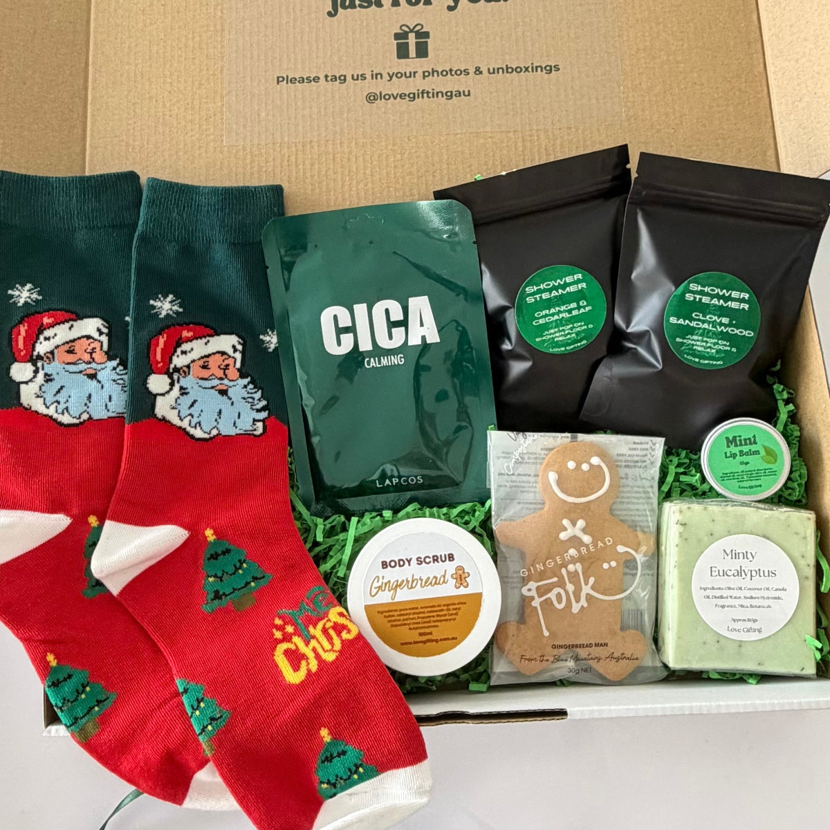 Men's Christmas self-care gift box with Santa socks, LAPCOS CICA face mask, shower steamers, gingerbread treats and minty skincare products.
